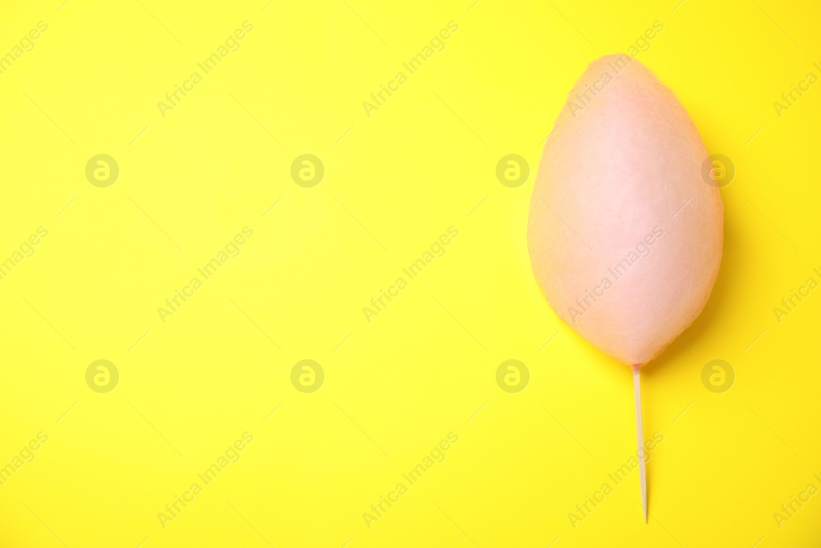 Photo of Sweet pink cotton candy on yellow background, top view. Space for text