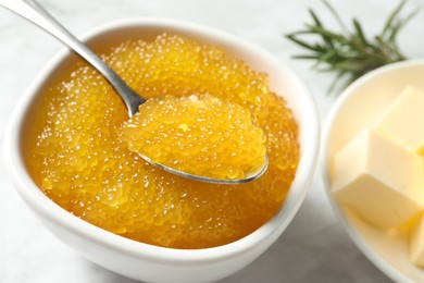 Photo of Fresh pike caviar in bowl, spoon and butter on table, closeup