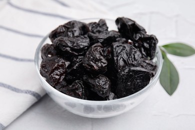Photo of Sweet dried prunes in bowl on light table, closeup