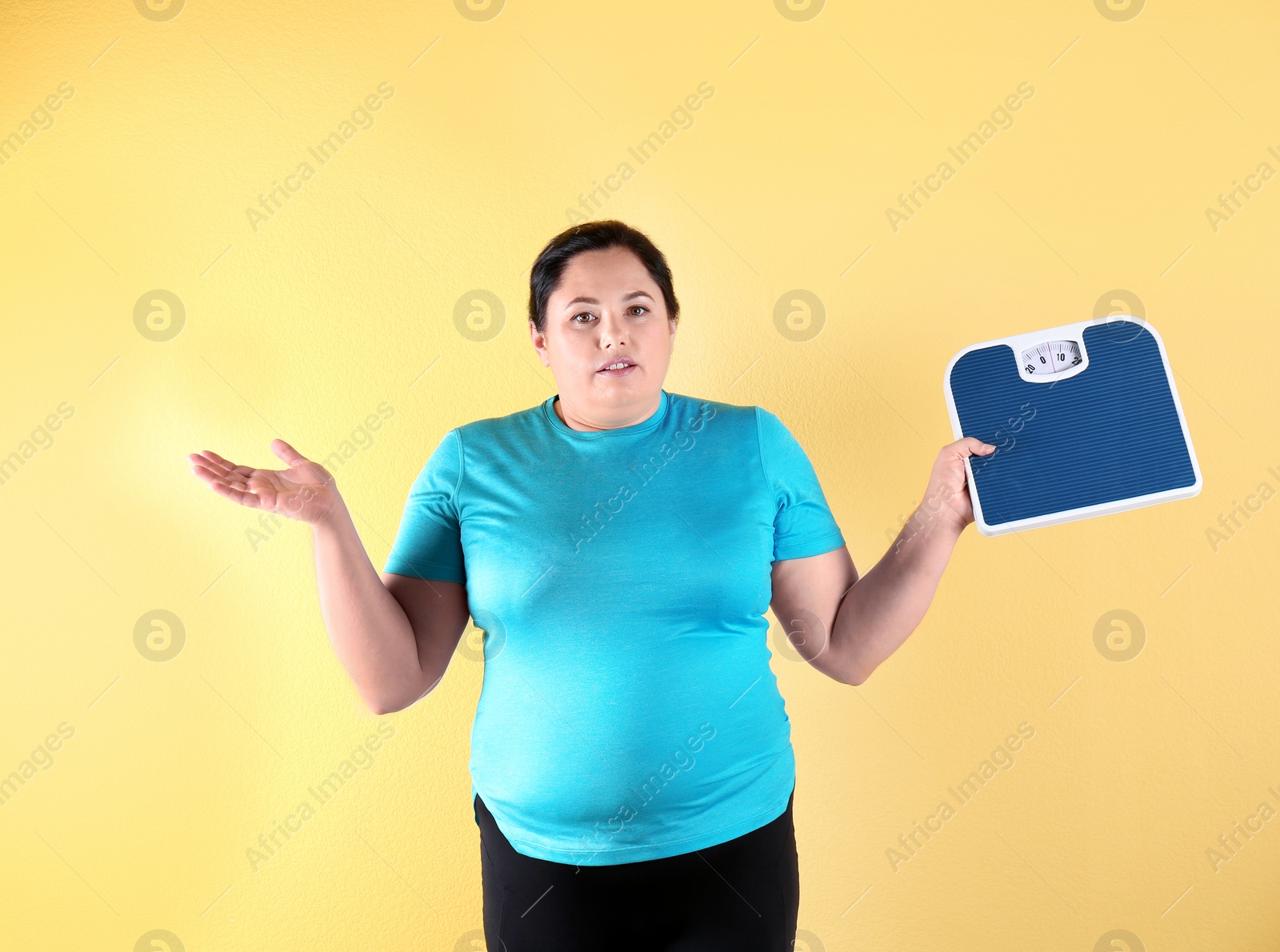 Photo of Overweight woman in sportswear with scales on color background