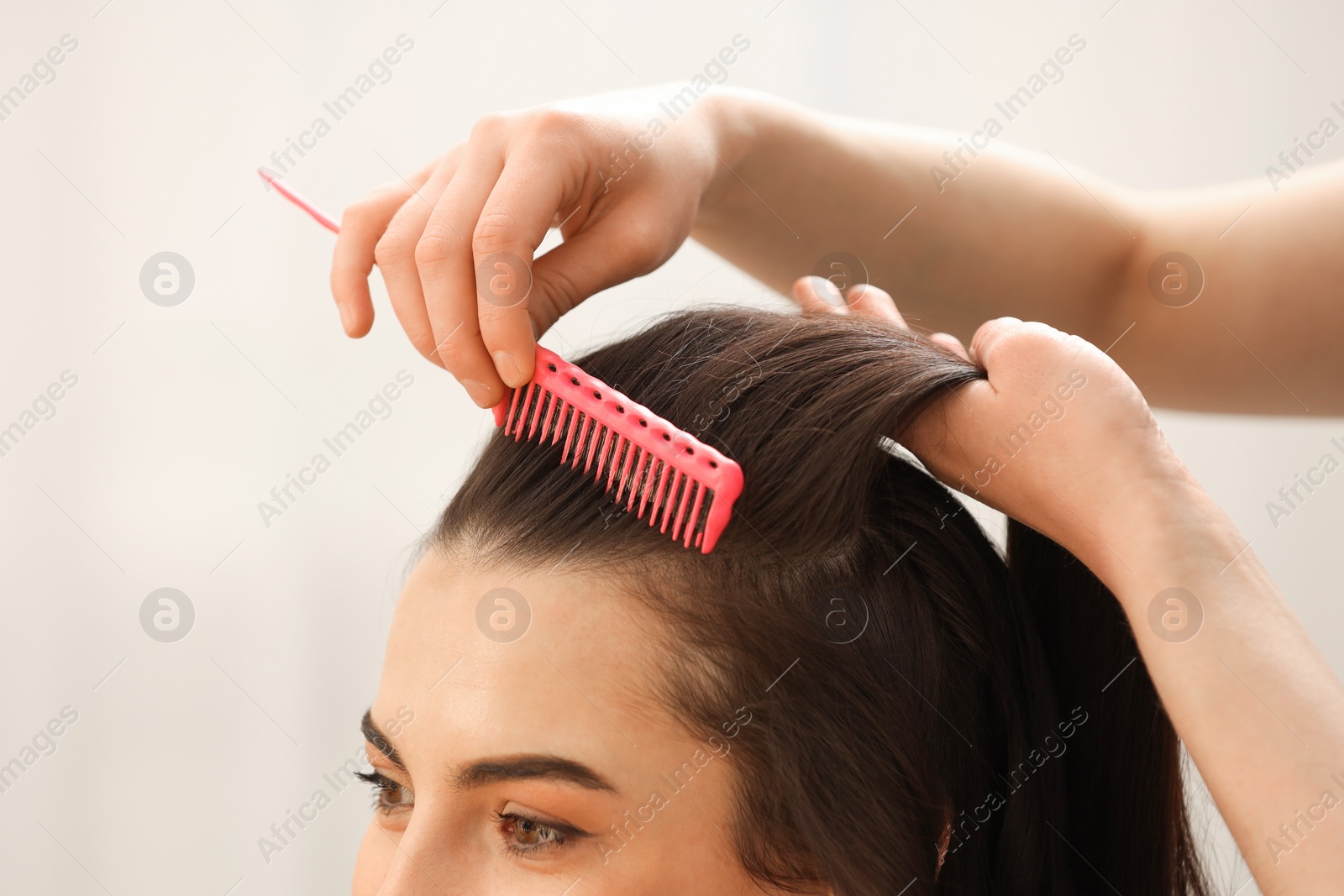 Photo of Hair styling. Professional hairdresser combing woman's hair indoors, closeup