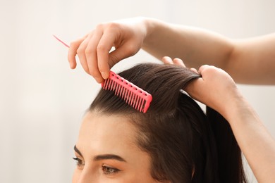 Hair styling. Professional hairdresser combing woman's hair indoors, closeup