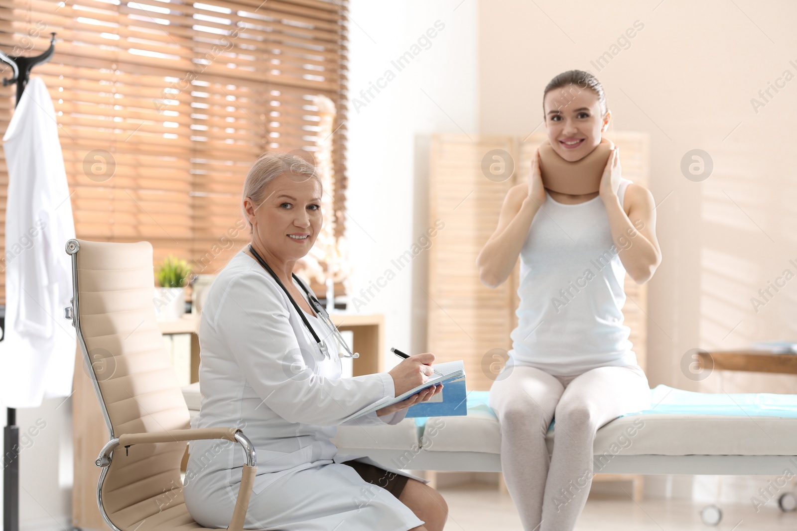 Photo of Female orthopedist examining patient with injured neck in clinic