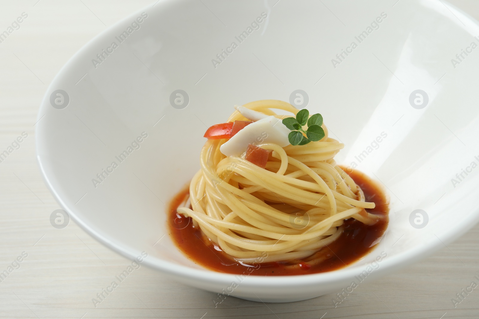 Photo of Tasty spaghetti with sauce on white wooden table, closeup. Exquisite presentation of pasta dish