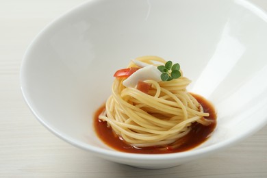 Tasty spaghetti with sauce on white wooden table, closeup. Exquisite presentation of pasta dish