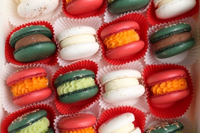 Different tasty Christmas macarons on white table, flat lay