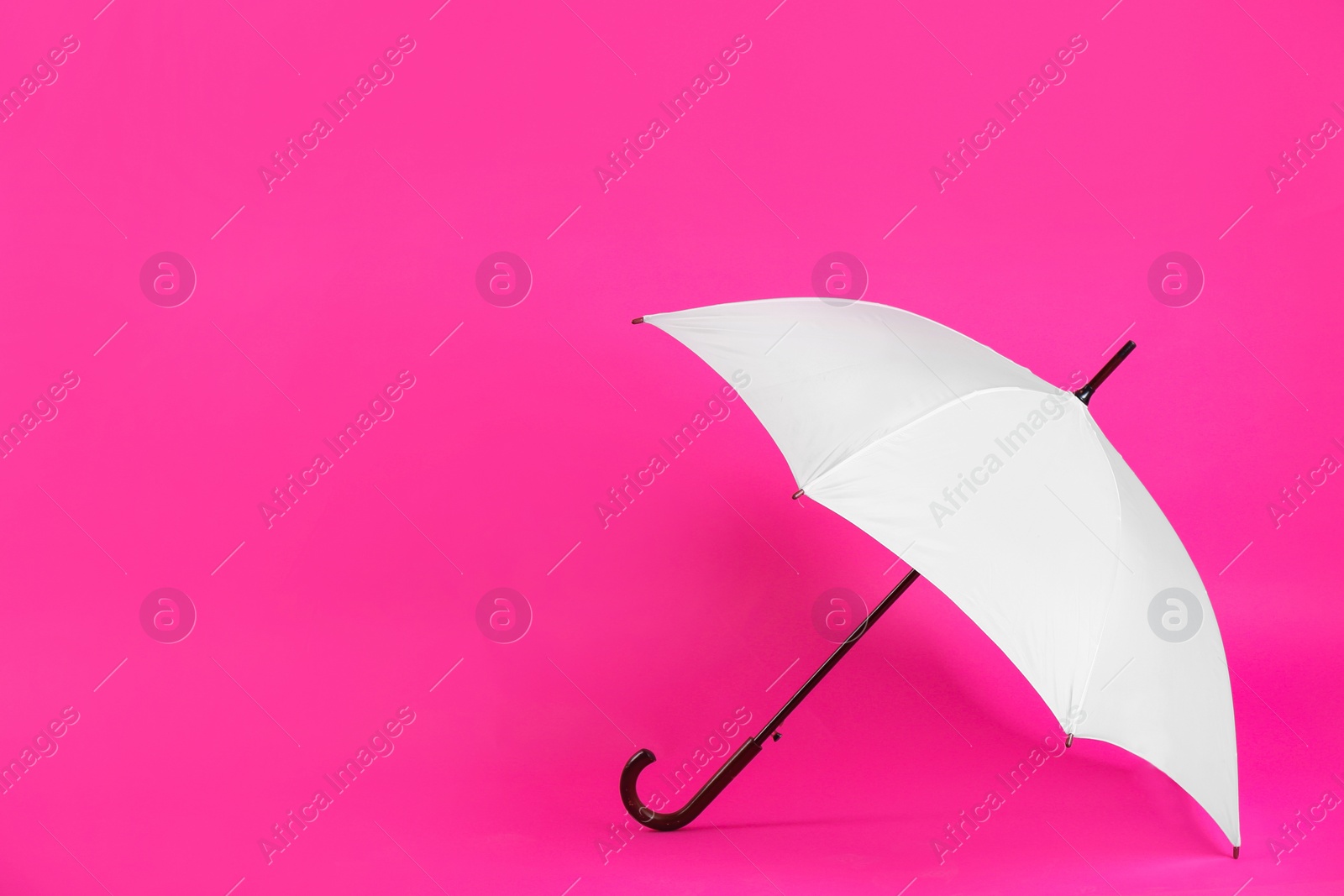 Photo of Beautiful white umbrella on pink background. Space for text