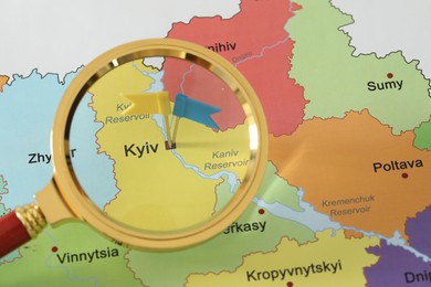 Photo of Map of Ukraine with yellow and blue flag push pins placed on Kyiv, view through magnifying glass