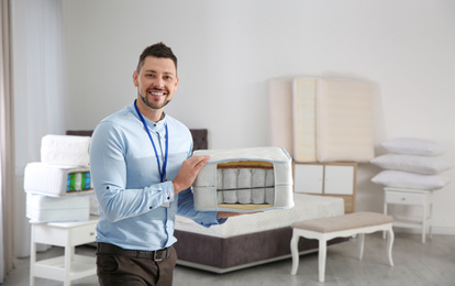 Photo of Salesman with section of mattress in furniture store