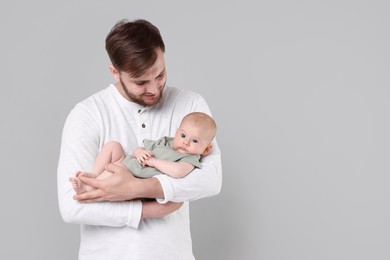 Photo of Father with his cute baby on grey background, space for text