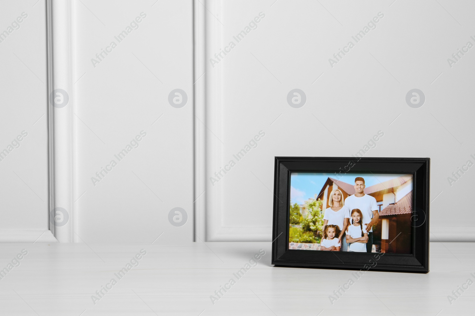 Photo of Framed family photo on white wooden table indoors, space for text