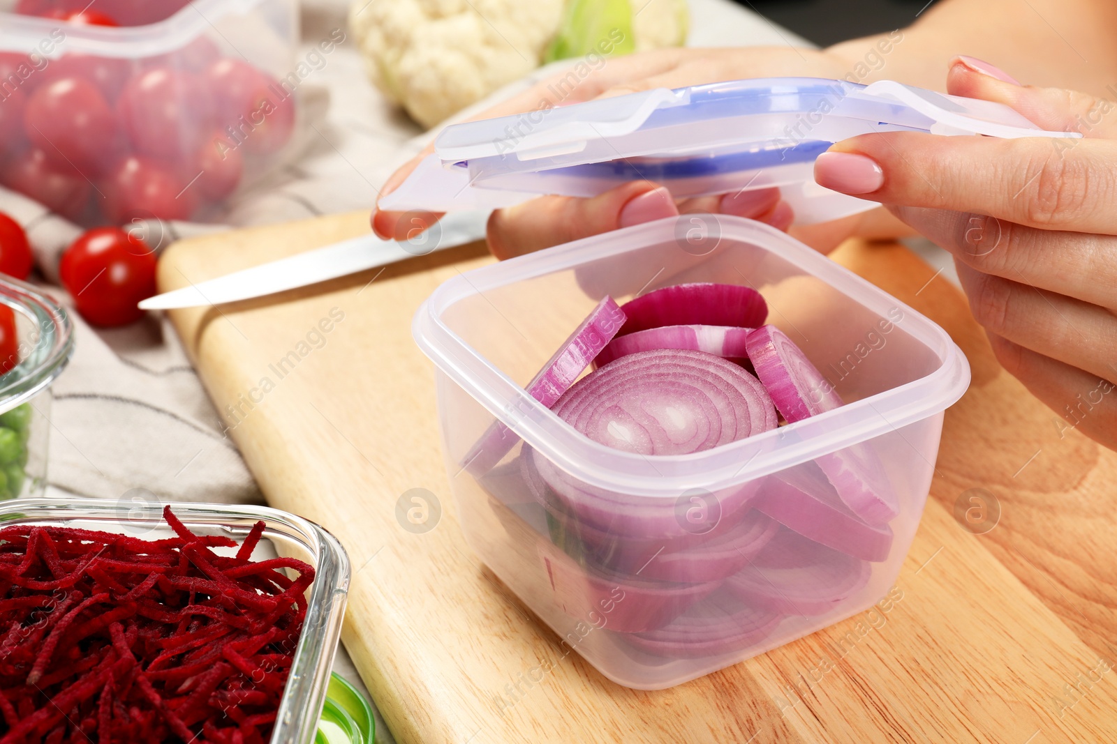 Photo of Woman closing plastic container with lid at table, closeup. Food storage