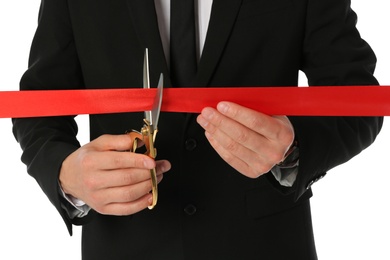 Man in office suit cutting red ribbon isolated on white, closeup