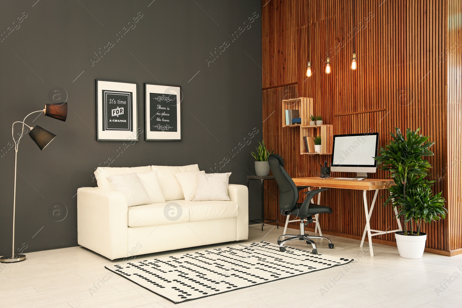 Photo of Comfortable workplace with computer near wooden wall in stylish room interior. Home office design