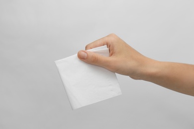 Woman holding paper tissue on light background, closeup