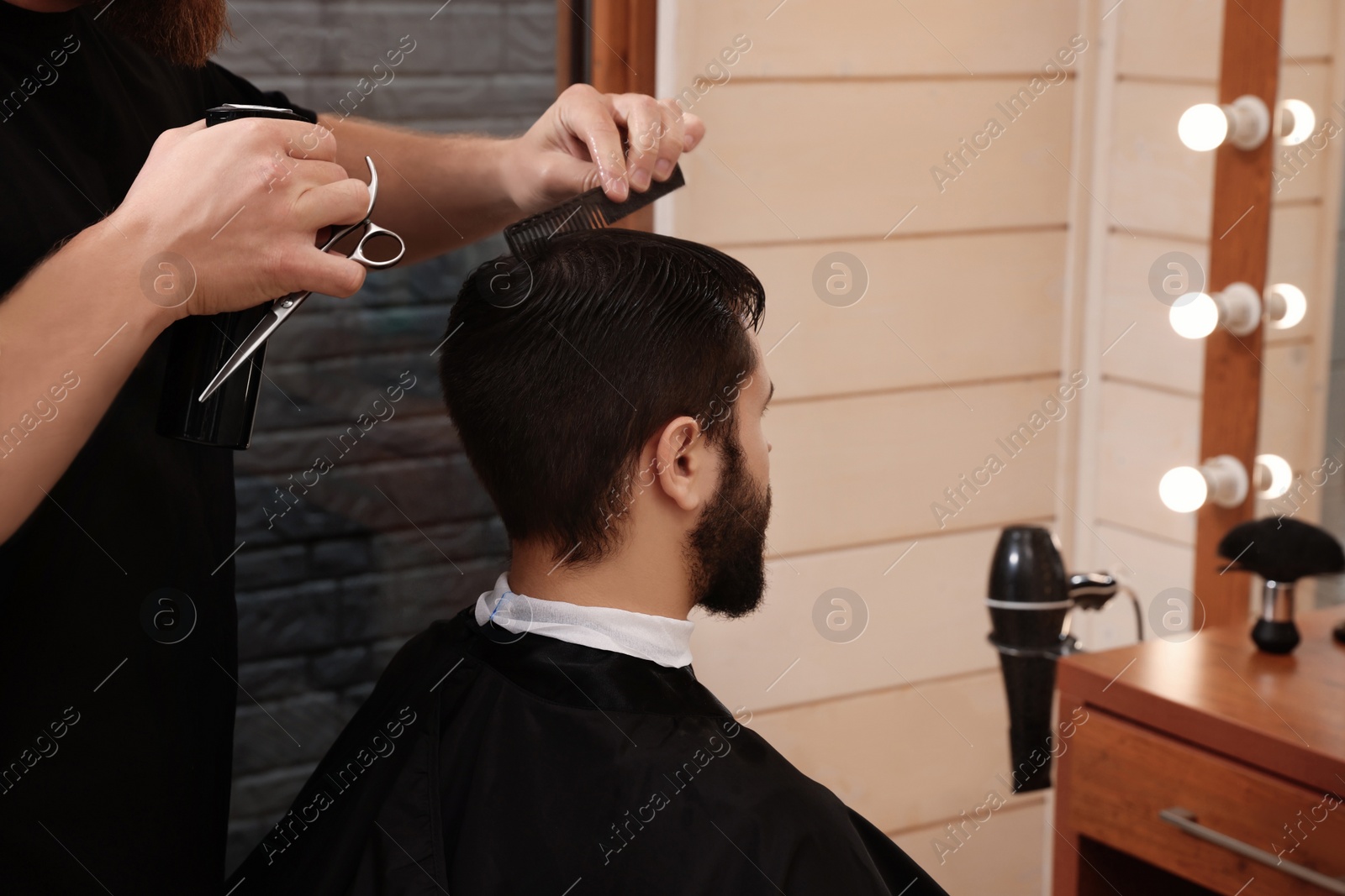 Photo of Professional hairdresser working with client in barbershop, closeup