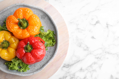 Photo of Tasty stuffed bell peppers on white marble table, top view. Space for text