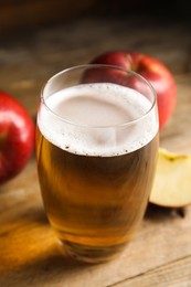 Photo of Glass of delicious apple cider on wooden table, closeup