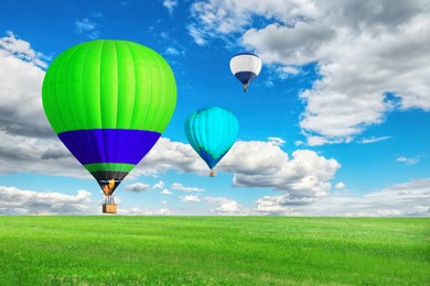 Image of Bright hot air balloons flying over green field