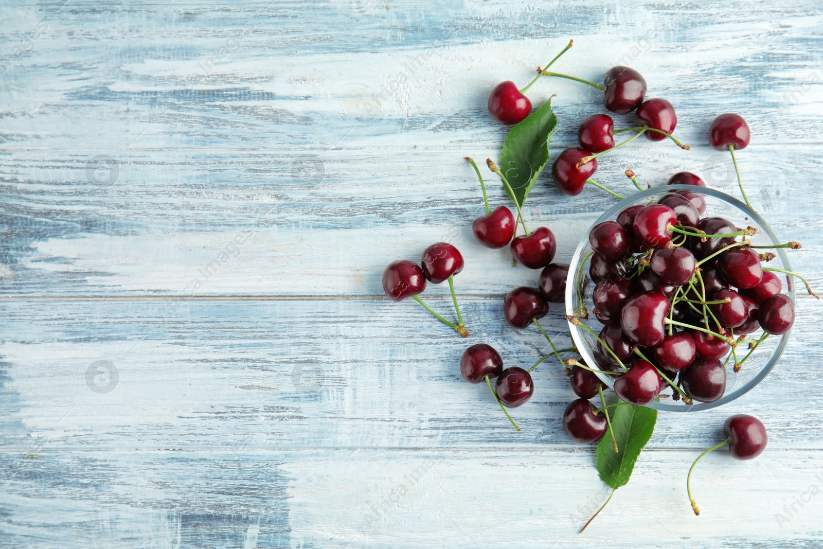 Photo of Bowl with sweet red cherries on wooden table, top view