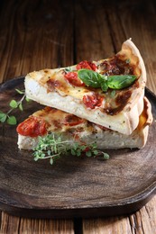 Photo of Pieces of delicious homemade quiche with prosciutto, tomatoes and greens on wooden table