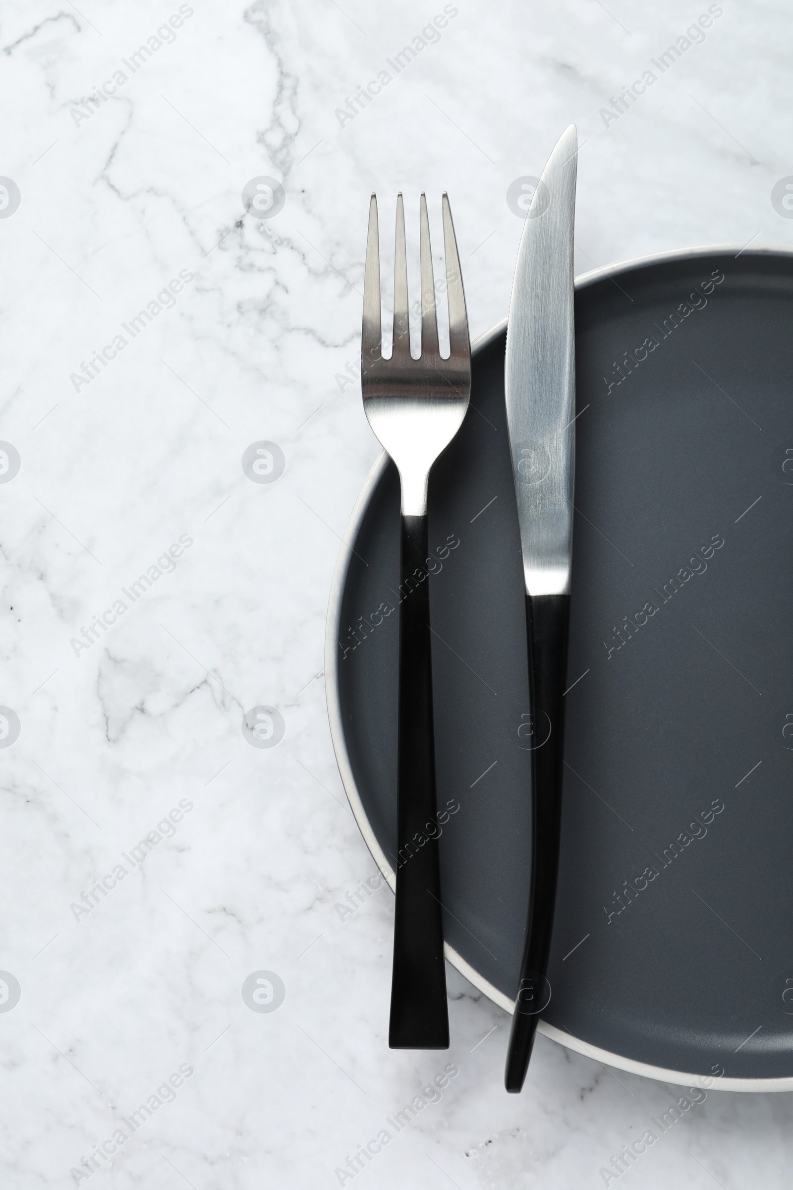 Photo of Stylish cutlery and plate on white marble table, top view