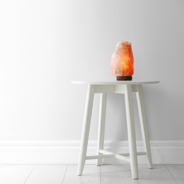 Himalayan salt lamp on table against  white wall. Space for text