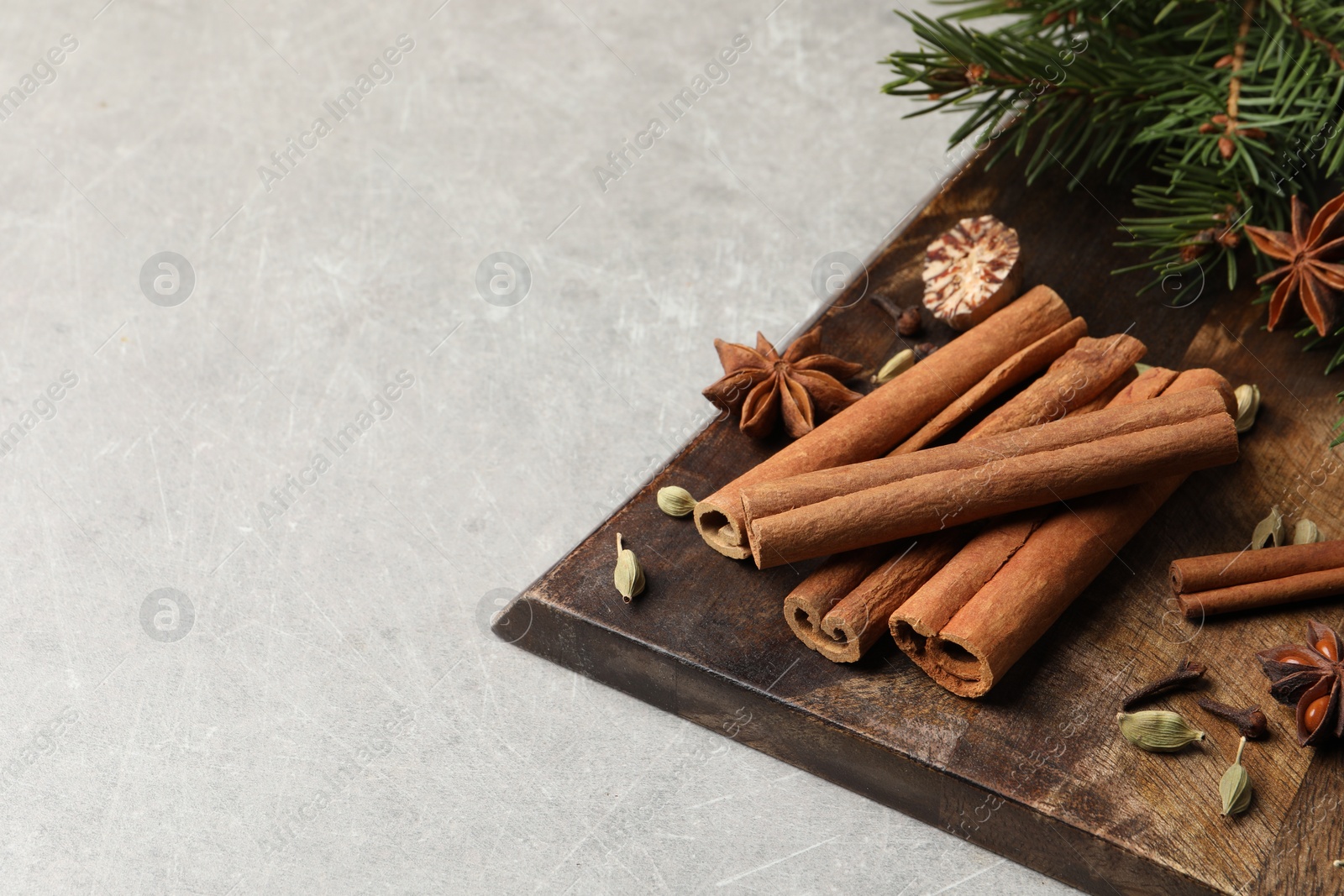 Photo of Board with different aromatic spices and fir branches on light table. Space for text