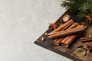 Board with different aromatic spices and fir branches on light table. Space for text