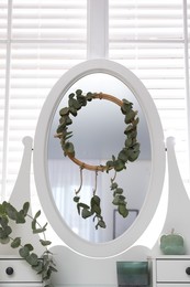 Stylish dressing table decorated with beautiful eucalyptus branches indoors