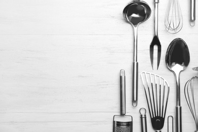 Photo of Different kitchen utensils on wooden background, top view with space for text