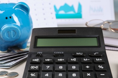 Photo of Calculator, piggy bank, money and notebooks on white table, closeup. Pension planning