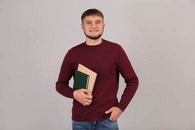 Young student with books on grey background
