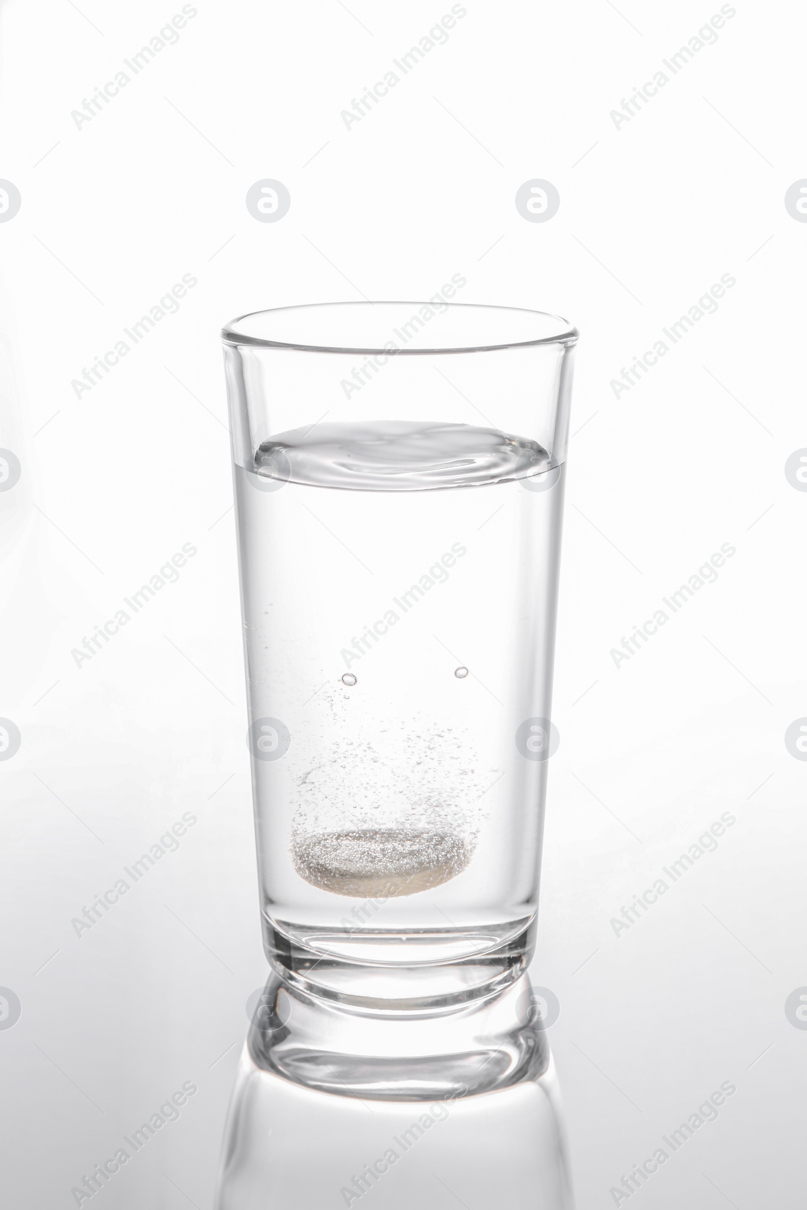 Photo of Effervescent pill dissolving in glass of water isolated on white