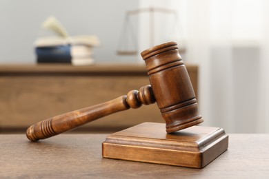 Photo of Wooden gavel and sound block on table indoors, closeup