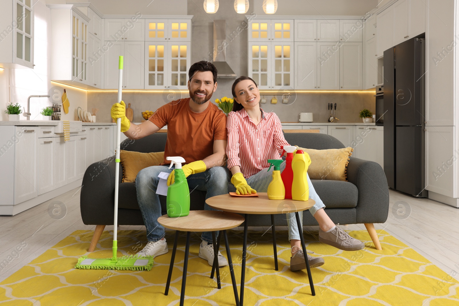 Photo of Spring cleaning. Lovely couple with mop and detergents in living room