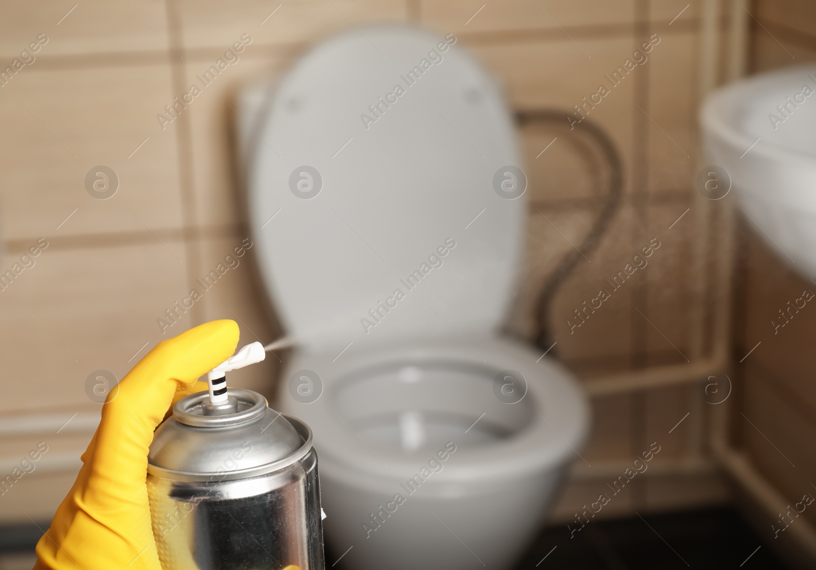 Photo of Person spraying air freshener in bathroom