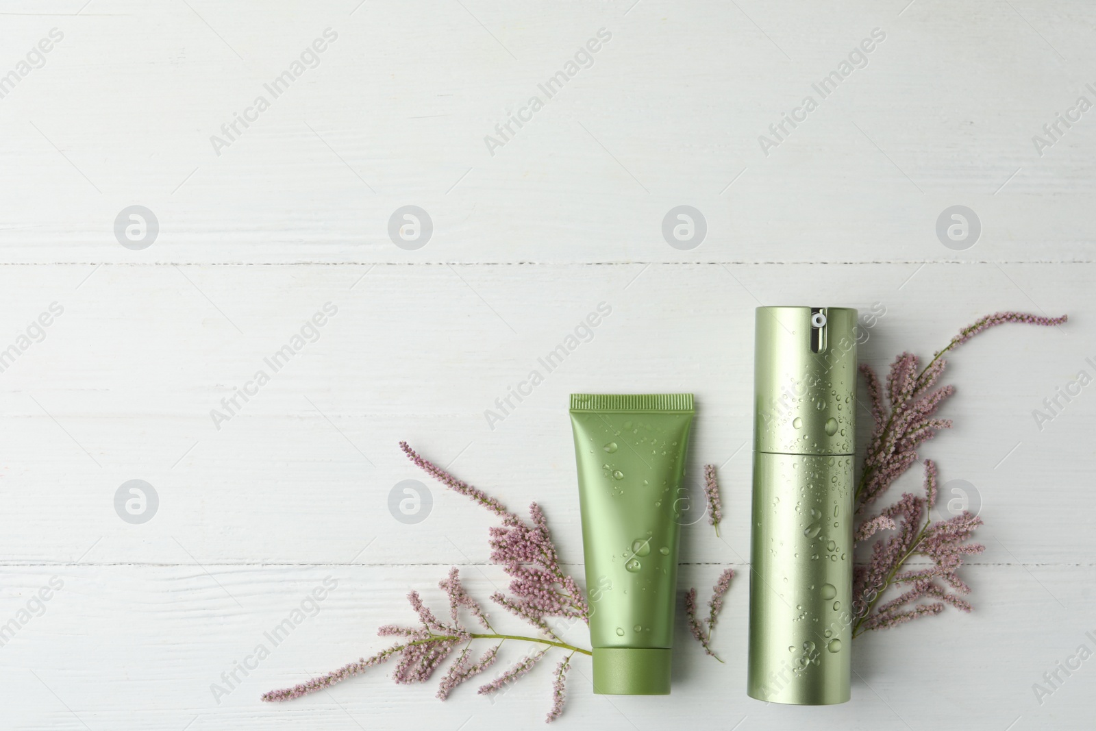 Photo of Cosmetic products and flowers on white wooden table, flat lay. Space for text