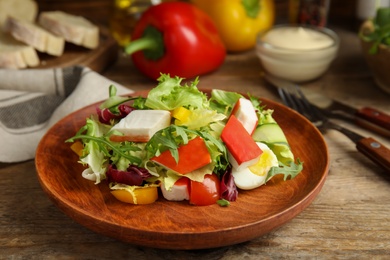 Photo of Delicious salad with crab sticks and lettuce on wooden table