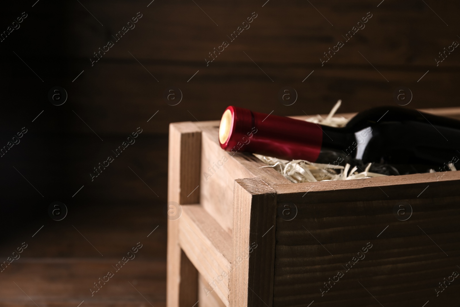 Photo of Open wooden crate with bottle of wine, closeup