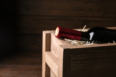 Photo of Open wooden crate with bottle of wine, closeup
