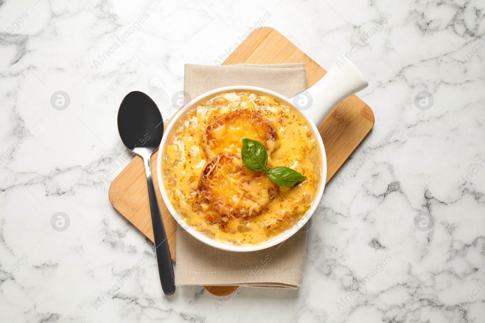 Photo of Tasty homemade french onion soup served on white marble table, flat lay