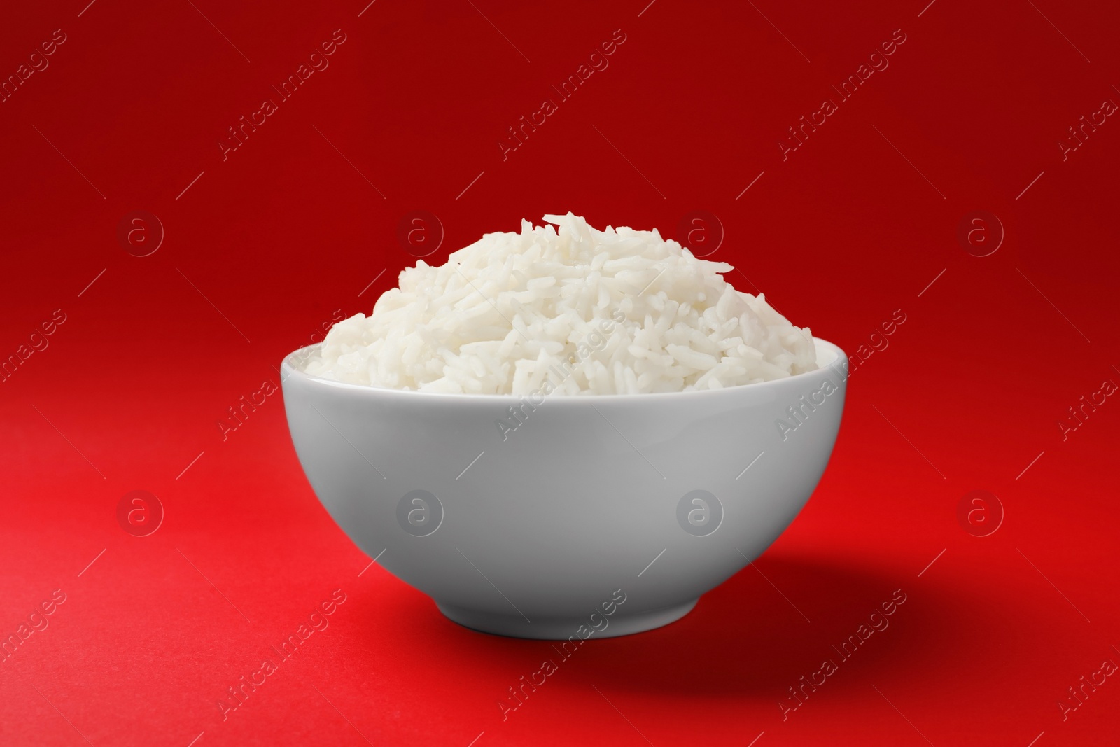 Photo of Bowl of tasty cooked rice on color background