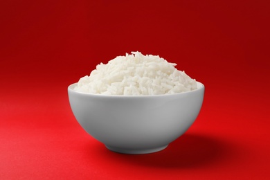 Bowl of tasty cooked rice on color background