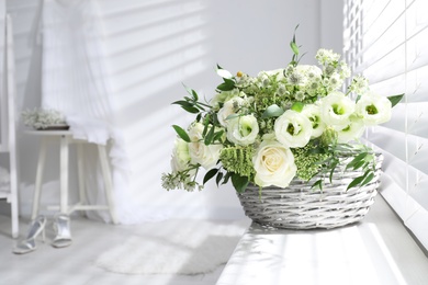 Photo of Basket with beautiful wedding flowers on window sill in room