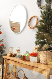 Potted fir tree and gift boxes on wooden table indoors. Christmas decoration