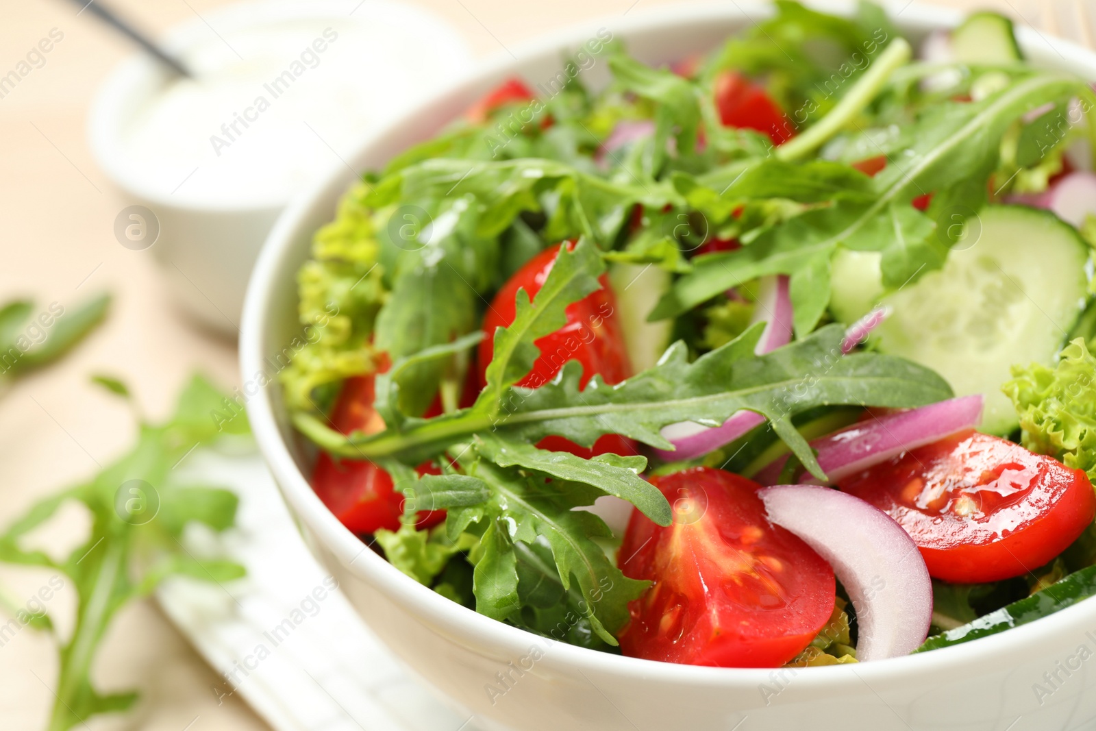 Photo of Delicious salad with arugula and vegetables in bowl, closeup