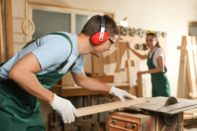 Photo of Professional carpenter with wooden plank in workshop
