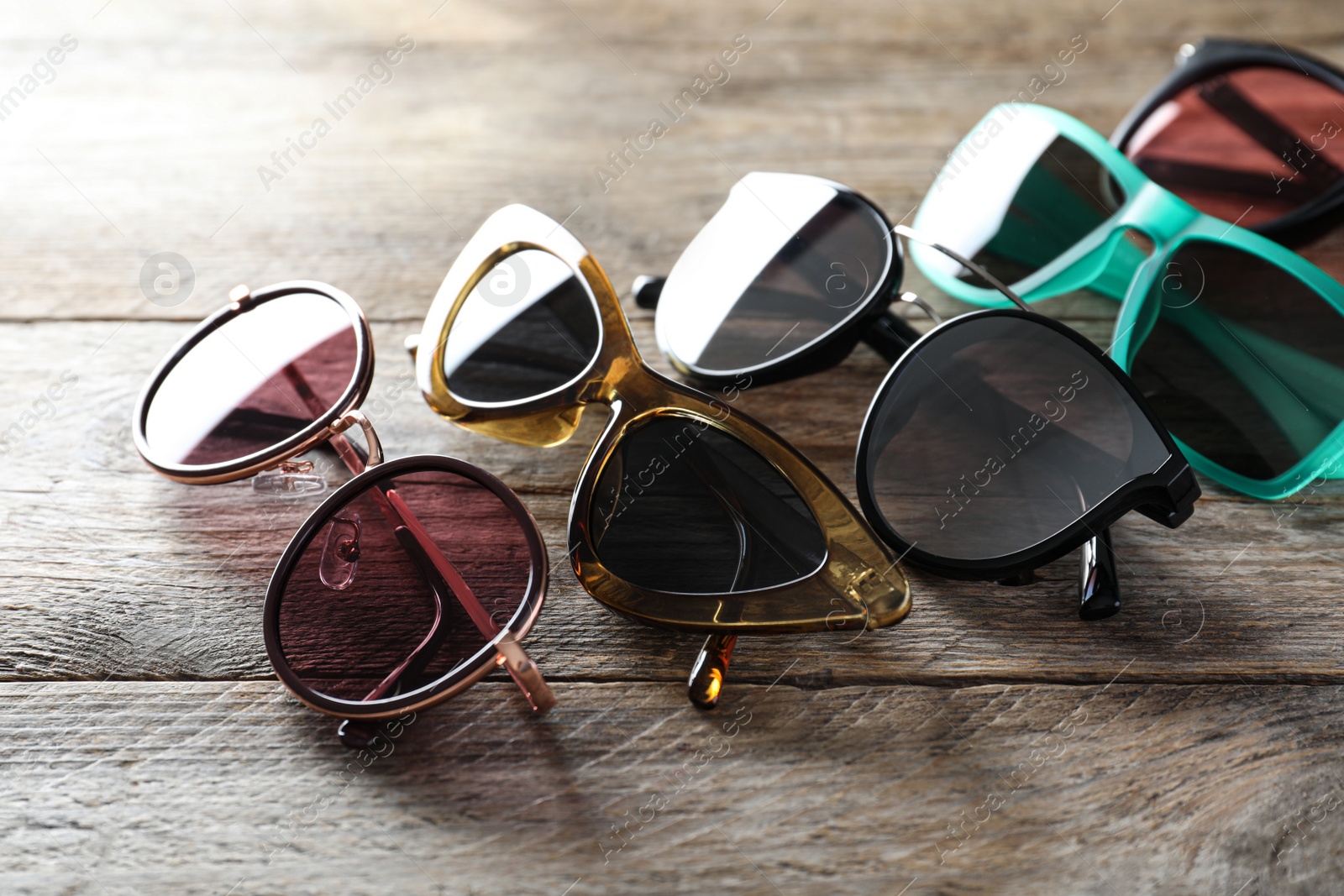 Photo of Many different stylish sunglasses on wooden background