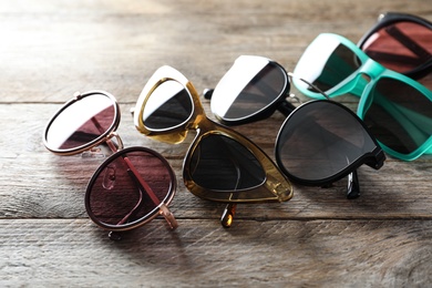 Photo of Many different stylish sunglasses on wooden background
